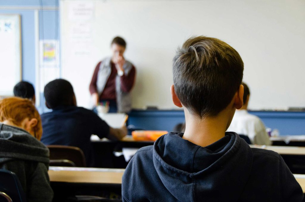 A student seated in a classroom viewed from behind