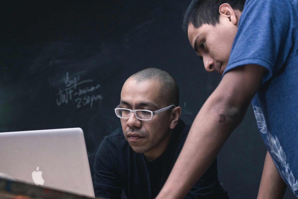 A student looking at a computer screen with their teacher