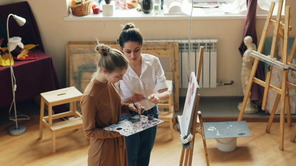 A teacher working one-on-one with a student in an art studio