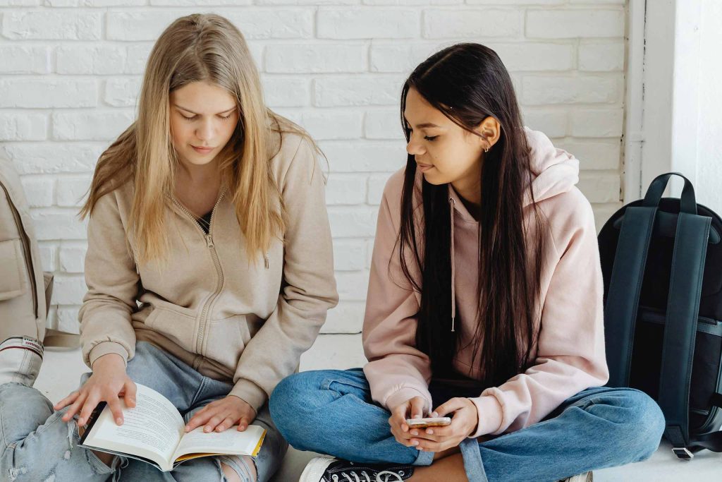 Two students, seated on the floor, study together