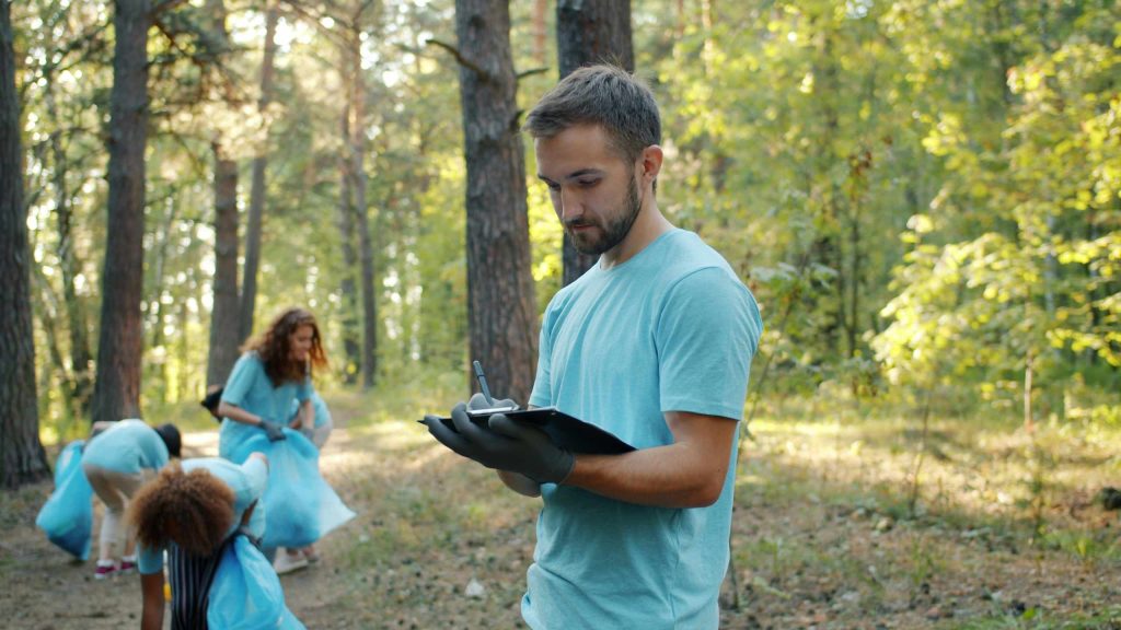 A faculty member takes attendance at a clean up day in the woods.