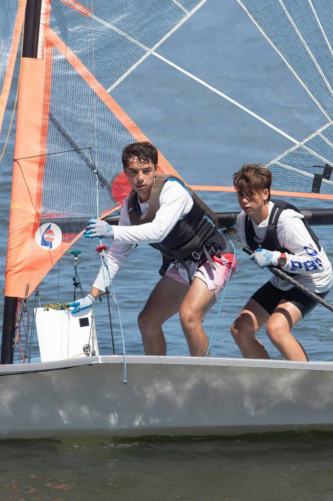 Two students on a small sailboat, one pulls up the centerboard
