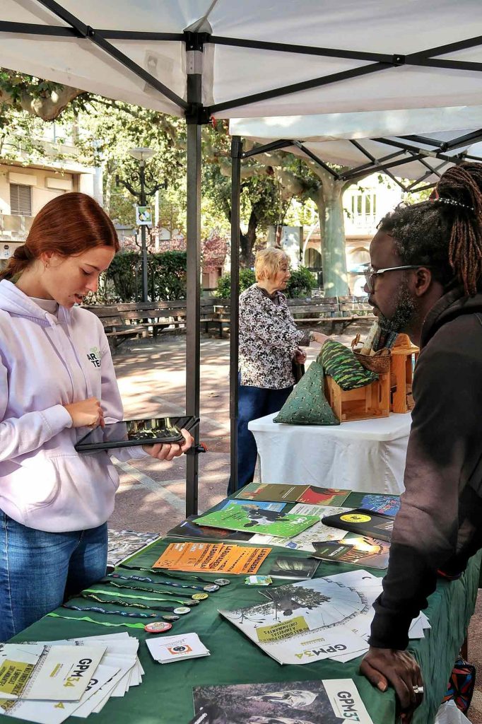 A student stands with a tablet at an information booth for an environmental organization, or similar organization