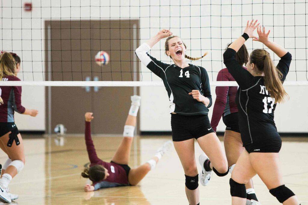 A girls' volleyball team celebrates a winning point